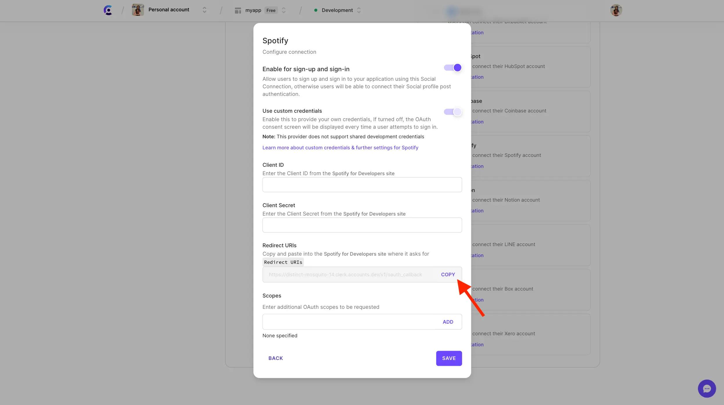 The Spotify settings modal in the Clerk Dashboard. A red arrow is pointing to the 'Redirect URI' copy button.